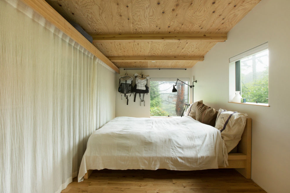 Mittelgroßes Industrial Hauptschlafzimmer mit weißer Wandfarbe, braunem Holzboden, freigelegten Dachbalken und Holzdielenwänden in Sonstige