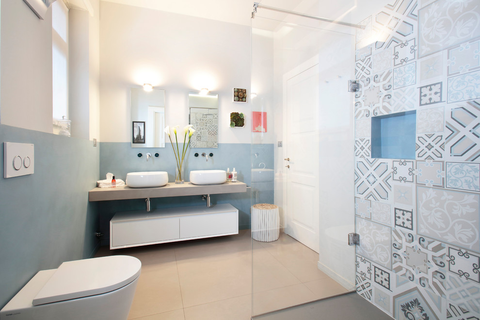 Photo of a mid-sized contemporary master bathroom in Turin with flat-panel cabinets, white cabinets, a corner shower, a wall-mount toilet, multi-coloured tile, blue walls, a vessel sink, beige floor and an open shower.