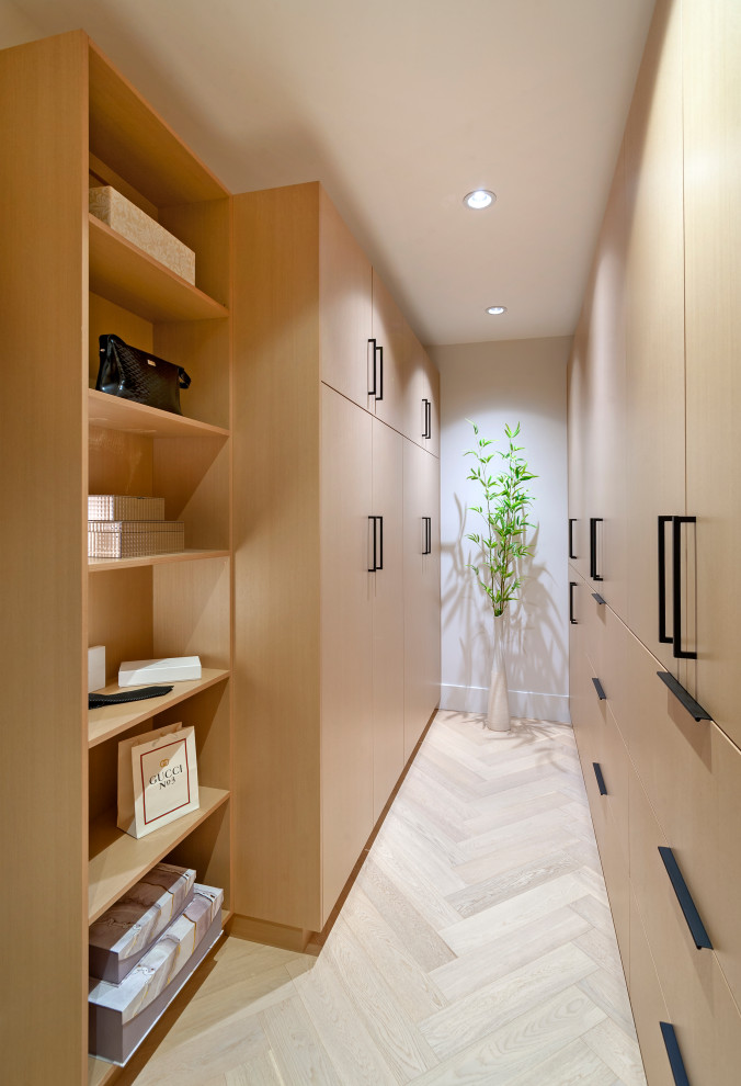 Design ideas for a mid-sized contemporary gender-neutral storage and wardrobe in Vancouver with flat-panel cabinets, light wood cabinets and light hardwood floors.