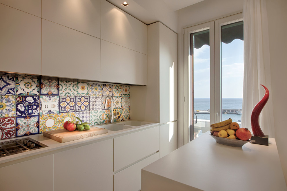 Design ideas for a small mediterranean single-wall separate kitchen in Other with an integrated sink, flat-panel cabinets, white cabinets, solid surface benchtops, multi-coloured splashback, ceramic splashback, stainless steel appliances, light hardwood floors, with island, yellow floor and white benchtop.