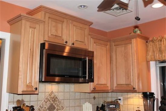 Elegant medium tone wood floor kitchen pantry photo in New York with a drop-in sink, raised-panel cabinets, light wood cabinets, beige backsplash and stainless steel appliances