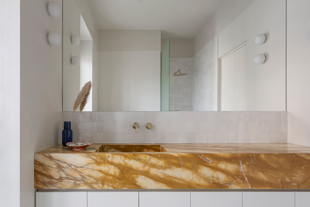 Inredning av ett modernt mellanstort gul gult badrum med dusch, med släta luckor, vita skåp, en kantlös dusch, en toalettstol med separat cisternkåpa, vit kakel, perrakottakakel, vita väggar, marmorgolv, ett avlångt handfat, marmorbänkskiva, beiget golv och med dusch som är öppen
