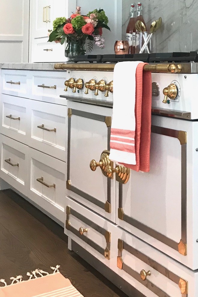 Open concept kitchen - large transitional l-shaped medium tone wood floor and brown floor open concept kitchen idea with a farmhouse sink, recessed-panel cabinets, white cabinets, quartzite countertops, white backsplash, stone slab backsplash, paneled appliances and an island