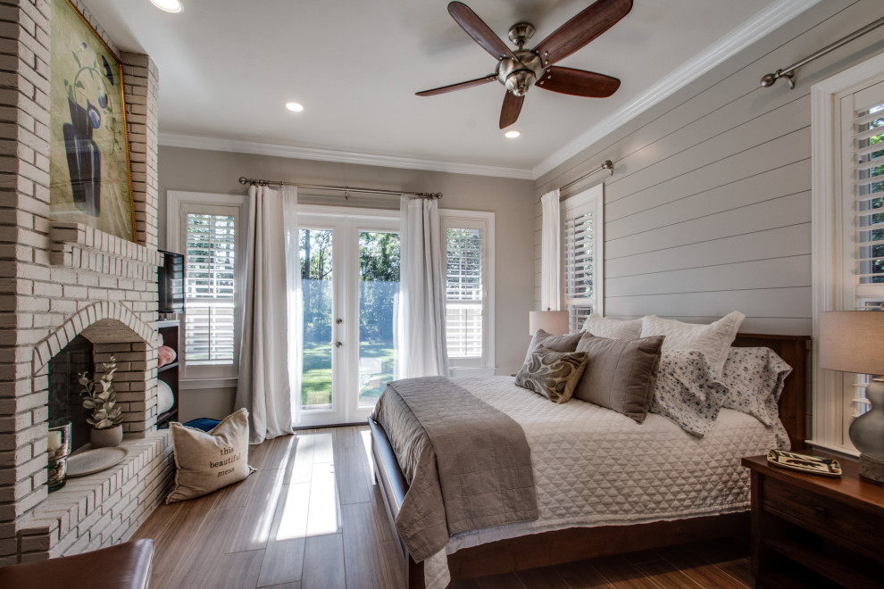 This is an example of a mid-sized transitional master bedroom in Other with grey walls, a standard fireplace, a brick fireplace surround, brown floor and planked wall panelling.