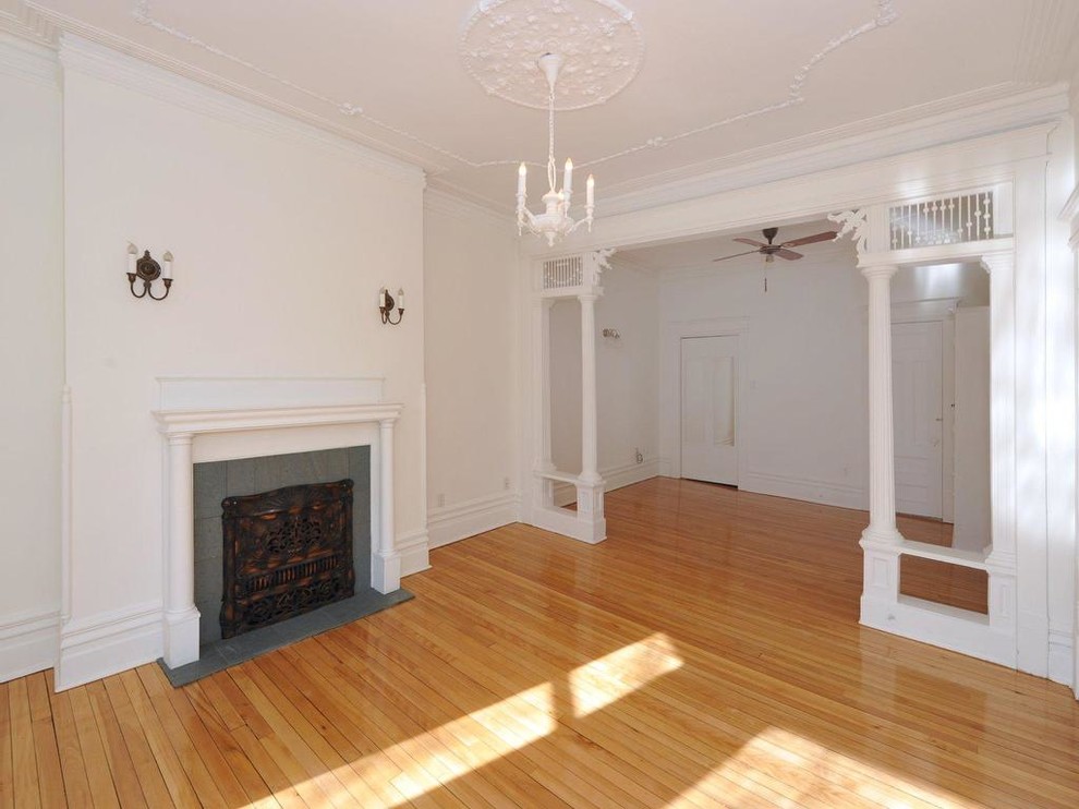 This is an example of a mid-sized traditional formal open concept living room in Montreal with white walls, medium hardwood floors, a standard fireplace, a tile fireplace surround, no tv and beige floor.