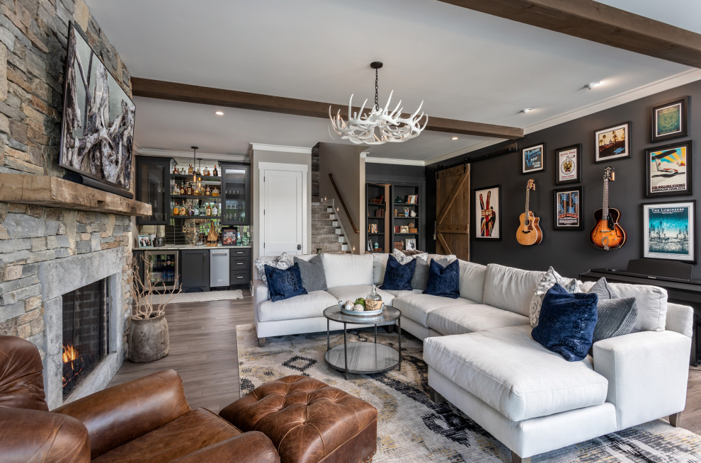 Large arts and crafts enclosed living room in Other with a home bar, grey walls, laminate floors, a standard fireplace, a stone fireplace surround, a wall-mounted tv, brown floor and exposed beam.