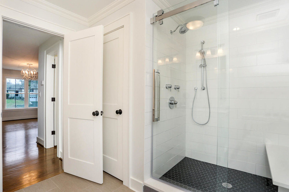 Photo of a mid-sized country master bathroom in New York with flat-panel cabinets, white cabinets, a two-piece toilet, white tile, subway tile, grey walls, porcelain floors, an undermount sink, marble benchtops, grey floor, a sliding shower screen and grey benchtops.