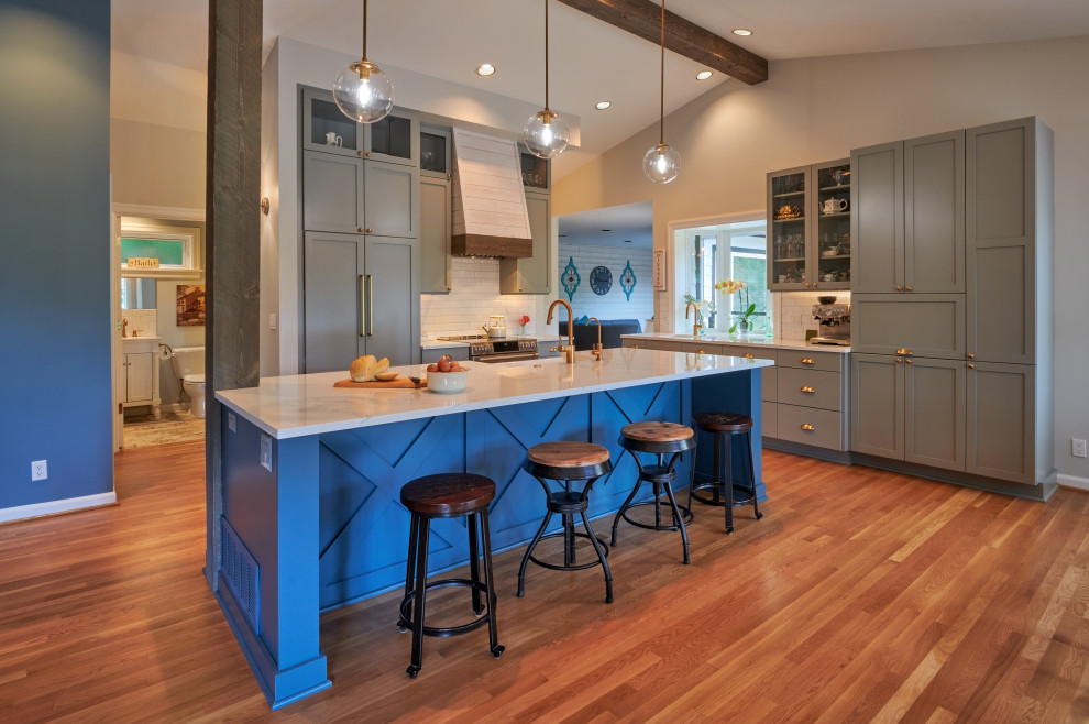 Medium sized country l-shaped open plan kitchen in Seattle with a submerged sink, shaker cabinets, grey cabinets, engineered stone countertops, white splashback, ceramic splashback, integrated appliances, medium hardwood flooring, an island, brown floors, white worktops and a vaulted ceiling.