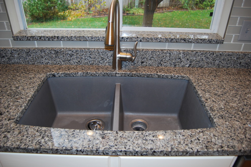 Inspiration for a small transitional l-shaped light wood floor and brown floor eat-in kitchen remodel with a double-bowl sink, raised-panel cabinets, white cabinets, granite countertops, gray backsplash, stainless steel appliances, an island and glass tile backsplash
