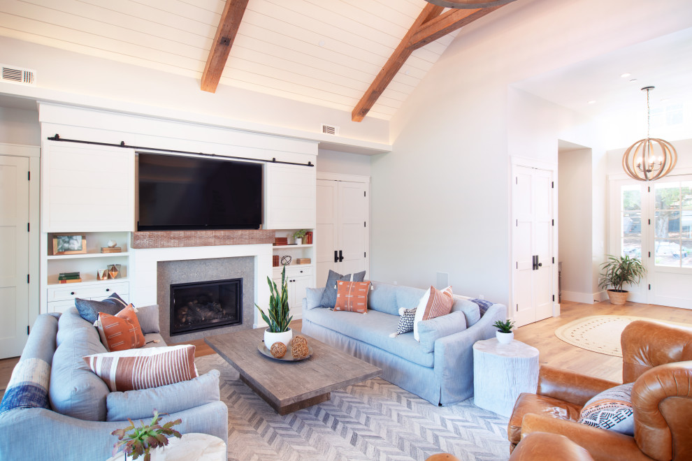 Exemple d'un salon nature ouvert avec un mur blanc, parquet clair, une cheminée standard, un téléviseur dissimulé, un sol beige, poutres apparentes, un plafond en lambris de bois et un plafond voûté.