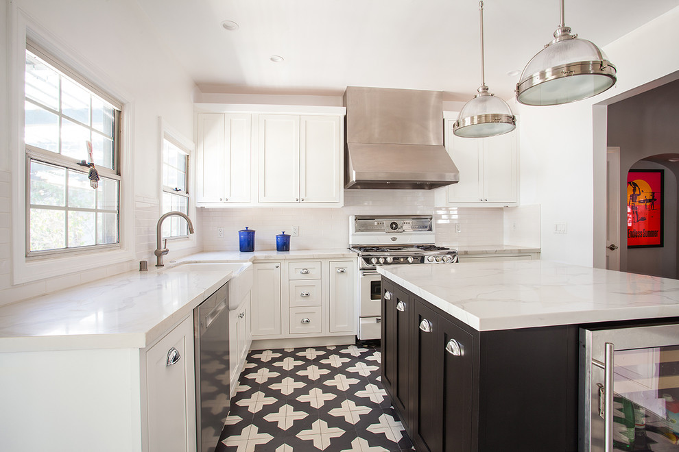 This is an example of a mid-sized contemporary l-shaped separate kitchen in Los Angeles with a farmhouse sink, beaded inset cabinets, white cabinets, quartz benchtops, white splashback, subway tile splashback, white appliances, cement tiles, with island and black floor.