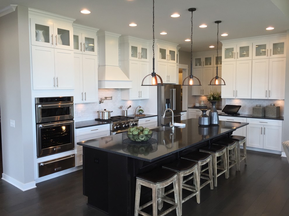 Inspiration for a large transitional l-shaped open plan kitchen in Indianapolis with an undermount sink, shaker cabinets, white cabinets, white splashback, subway tile splashback, stainless steel appliances, dark hardwood floors, with island and soapstone benchtops.