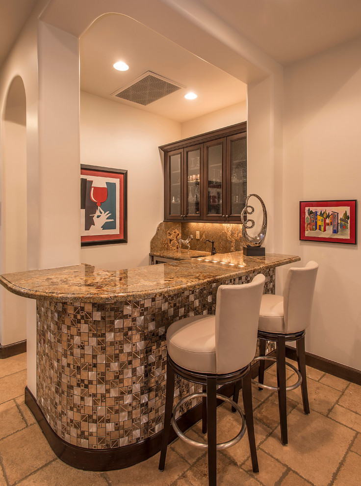 Photo of a mid-sized contemporary l-shaped seated home bar in Phoenix with dark wood cabinets, granite benchtops, stone slab splashback, an undermount sink, glass-front cabinets and travertine floors.