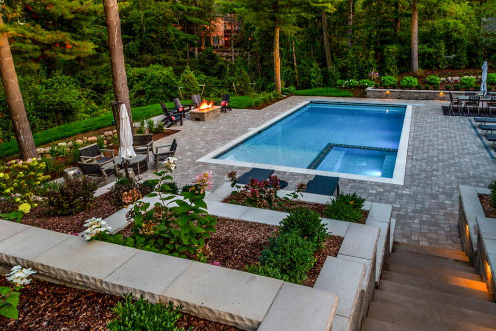 На фото: прямоугольный бассейн на заднем дворе в классическом стиле с джакузи и покрытием из каменной брусчатки
