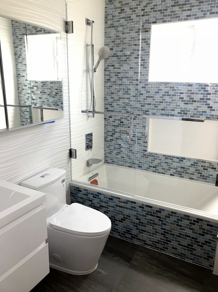 This is an example of a small modern bathroom in San Francisco with flat-panel cabinets, white cabinets, an alcove tub, a shower/bathtub combo, a one-piece toilet, blue tile, glass tile, porcelain floors, an integrated sink, grey floor, a sliding shower screen and white benchtops.