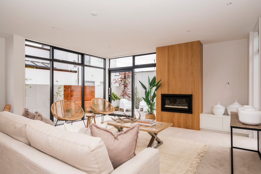 Inspiration for a mid-sized scandinavian formal open concept living room in Christchurch with white walls, carpet, a ribbon fireplace, a wood fireplace surround, a wall-mounted tv and beige floor.