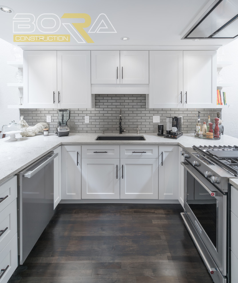 Example of a mid-sized transitional u-shaped dark wood floor and brown floor eat-in kitchen design with an undermount sink, recessed-panel cabinets, white cabinets, wood countertops, metallic backsplash, ceramic backsplash, stainless steel appliances and a peninsula