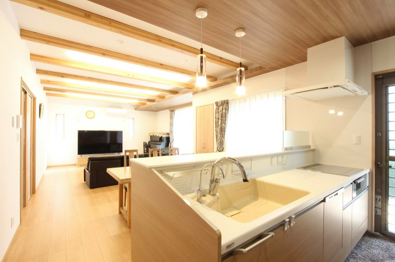 Large single-wall open plan kitchen in Fukuoka with an integrated sink, beaded inset cabinets, beige cabinets, marble benchtops, white splashback, glass sheet splashback, stainless steel appliances, plywood floors, beige floor, white benchtop and exposed beam.
