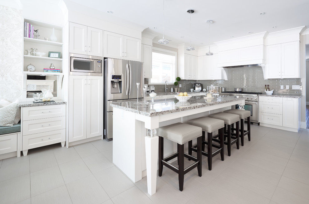 Design ideas for a mid-sized transitional l-shaped kitchen in Vancouver with an undermount sink, shaker cabinets, white cabinets, granite benchtops, grey splashback, glass tile splashback, stainless steel appliances, porcelain floors and with island.