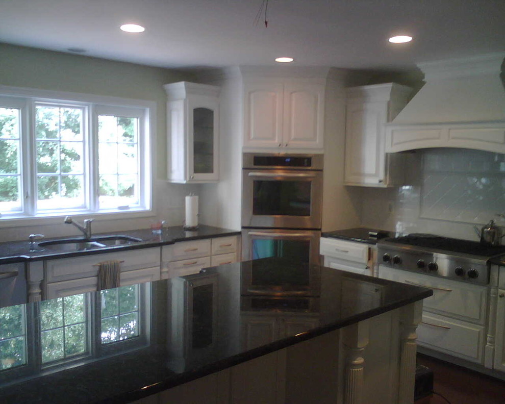 Dark wood floor kitchen photo in DC Metro with white cabinets and stainless steel appliances