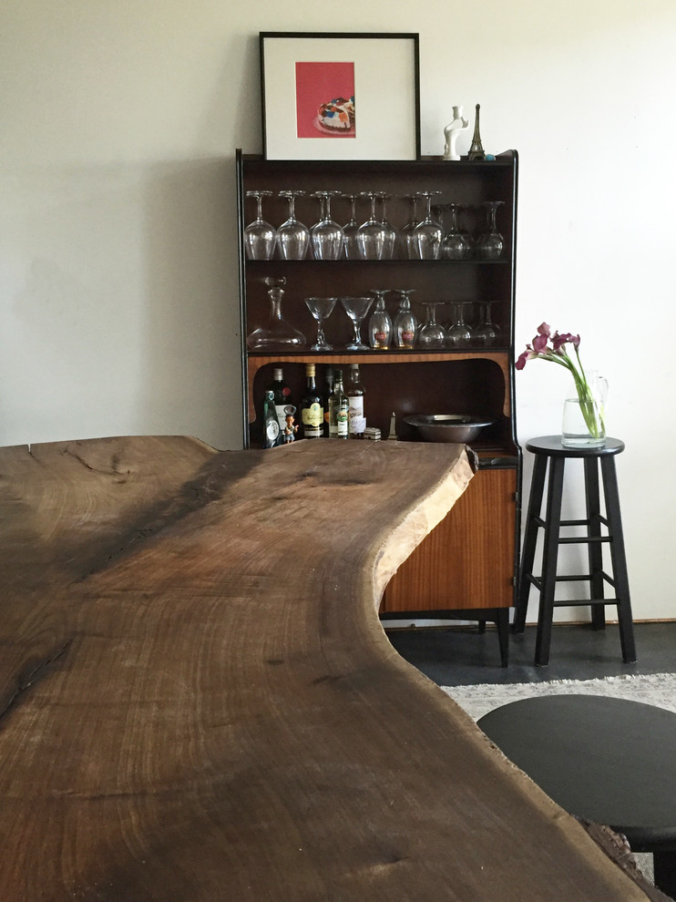 This is an example of a mid-sized eclectic single-wall home bar in Los Angeles with open cabinets, medium wood cabinets and wood benchtops.