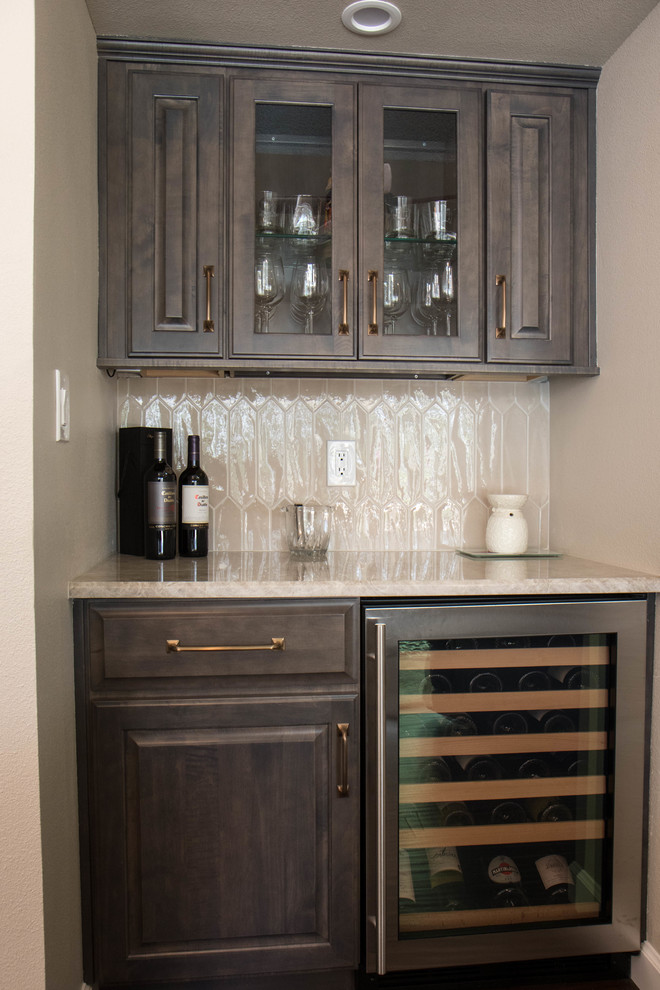 This is an example of a small transitional home bar in Orlando with raised-panel cabinets, grey cabinets, quartzite benchtops, grey splashback, porcelain splashback, porcelain floors, brown floor and grey benchtop.