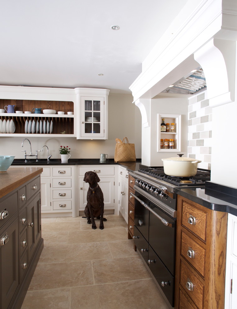 Medium sized traditional l-shaped enclosed kitchen in Essex with a submerged sink, flat-panel cabinets, white cabinets, granite worktops, multi-coloured splashback, ceramic splashback, black appliances, travertine flooring and an island.
