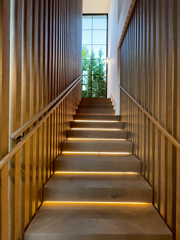 Große Treppe in U-Form mit Holz-Setzstufen und vertäfelten Wänden in Sonstige