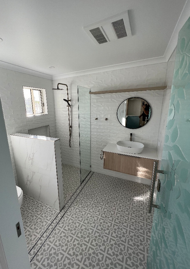 Пример оригинального дизайна: главная ванная комната среднего размера в стиле модернизм с фасадами с выступающей филенкой, светлыми деревянными фасадами, открытым душем, инсталляцией, керамической плиткой, белыми стенами, столешницей из искусственного кварца, открытым душем, нишей, тумбой под одну раковину и подвесной тумбой