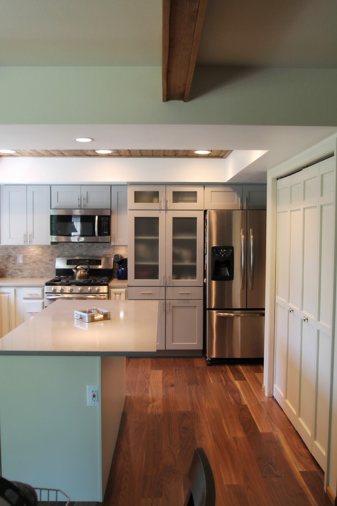 Large transitional l-shaped medium tone wood floor eat-in kitchen photo in Denver with an undermount sink, shaker cabinets, gray cabinets, quartz countertops, gray backsplash, stone tile backsplash, stainless steel appliances and an island