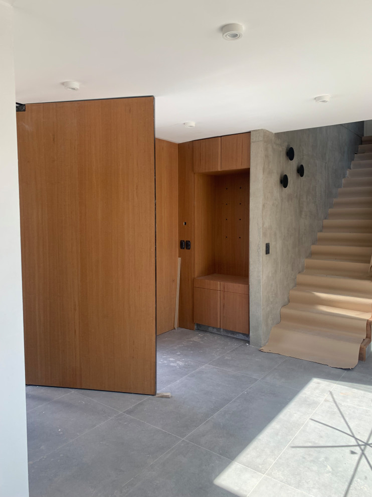 Idee per un ingresso o corridoio moderno con pareti marroni, pavimento in cemento, pavimento grigio e pareti in legno