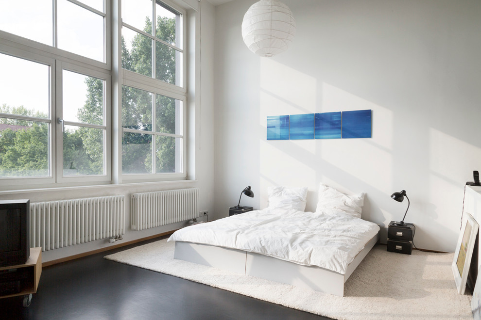 This is an example of a mid-sized industrial loft-style bedroom in Berlin with white walls and no fireplace.