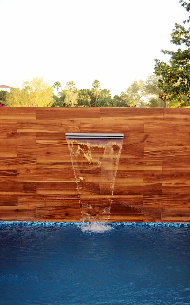 Photo of a small contemporary backyard rectangular lap pool in Other with a water feature.