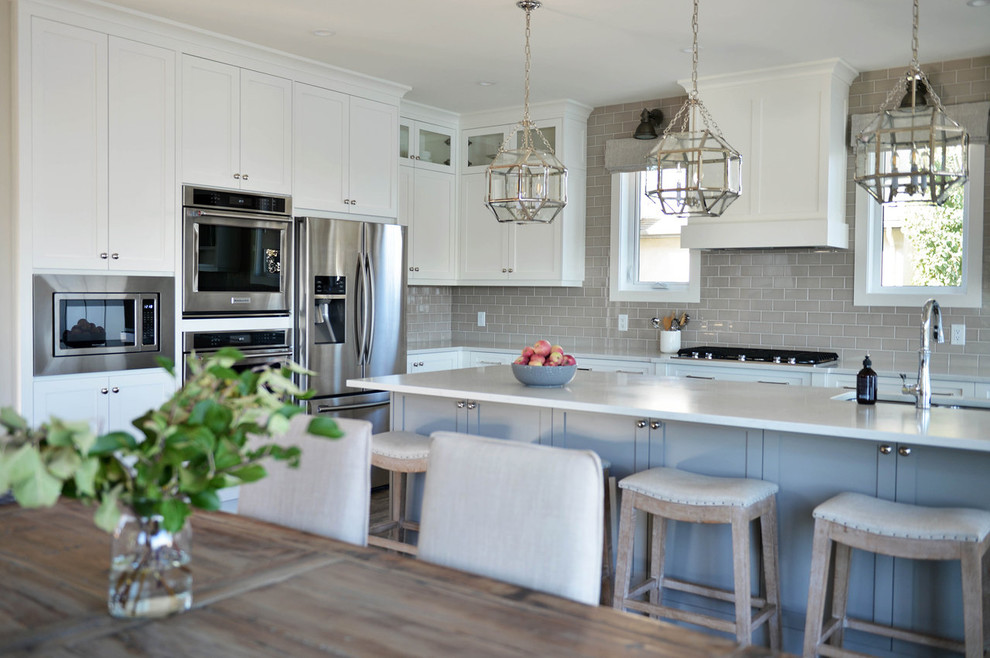 Example of a mid-sized transitional ceramic tile and beige floor eat-in kitchen design in Calgary with a double-bowl sink, shaker cabinets, white cabinets, quartz countertops, gray backsplash, ceramic backsplash, stainless steel appliances, an island and white countertops