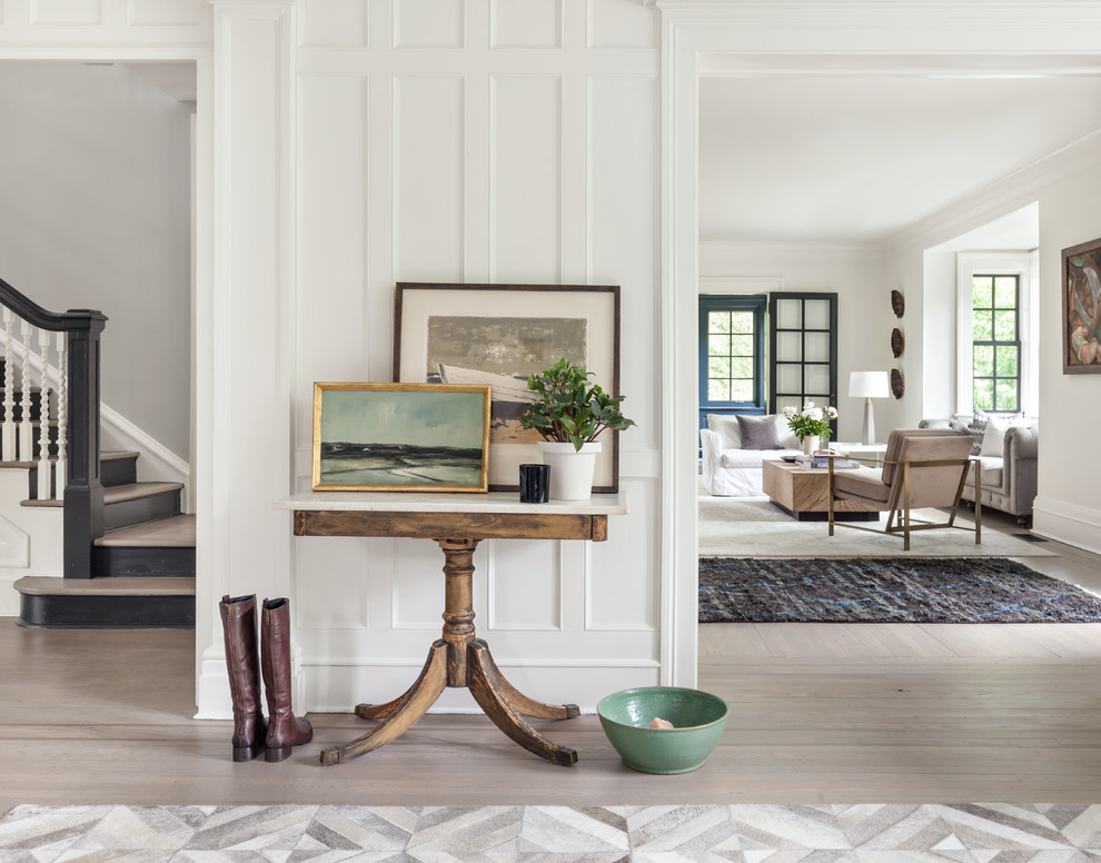 Inspiration for a transitional entry hall in New York with white walls, light hardwood floors and beige floor.