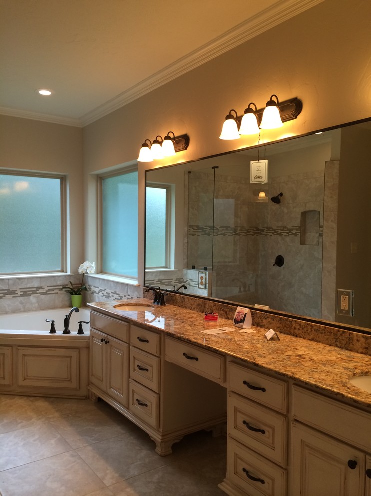 Photo of a mid-sized traditional master bathroom in Austin with an undermount sink, raised-panel cabinets, distressed cabinets, granite benchtops, a corner tub, a corner shower, a two-piece toilet, beige tile, ceramic tile, white walls, ceramic floors, beige floor and an open shower.