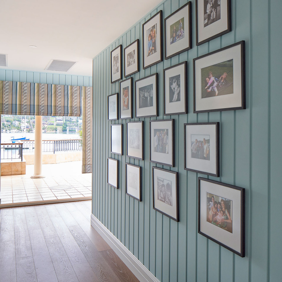 Diseño de salón abierto costero extra grande con paredes azules, suelo de madera oscura, suelo marrón y machihembrado