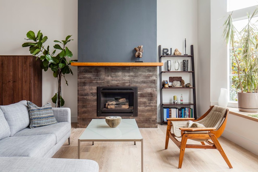 Photo of a mid-sized midcentury formal enclosed living room in San Francisco with white walls, light hardwood floors, a standard fireplace, a stone fireplace surround, no tv and beige floor.