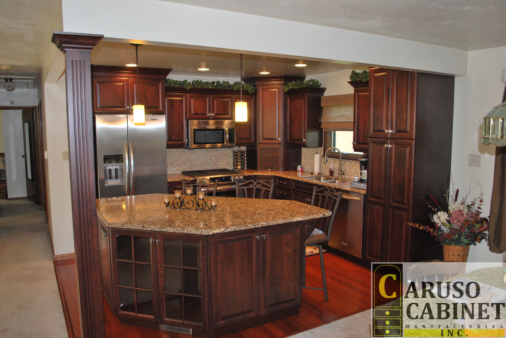 Eat-in kitchen - small traditional l-shaped medium tone wood floor eat-in kitchen idea with a double-bowl sink, raised-panel cabinets, dark wood cabinets, quartzite countertops, beige backsplash, ceramic backsplash, stainless steel appliances and an island