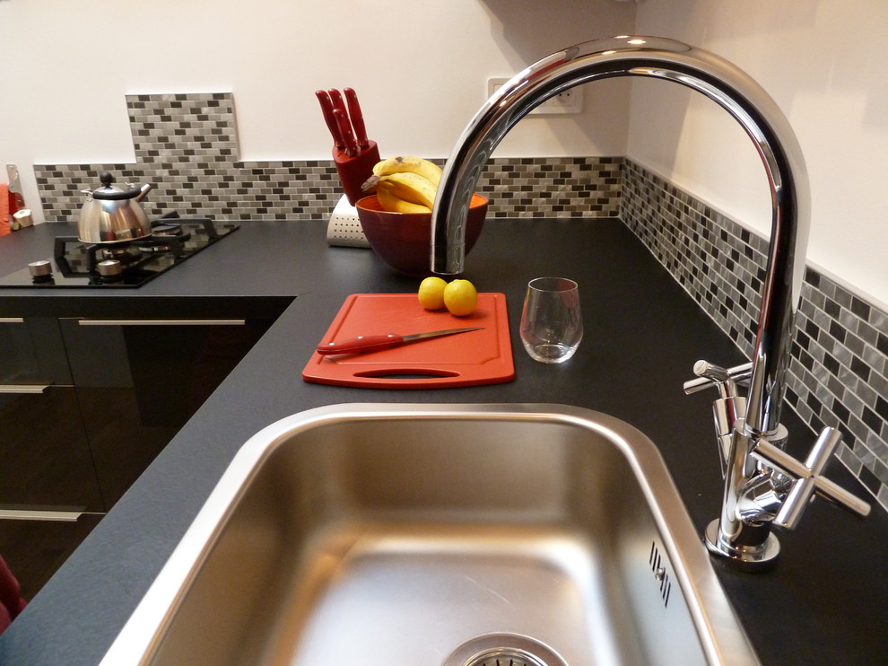 Aménagement de cuisine in U With un évier encastré, des portes de placard rouges, un plan de travail en stratifié, une crédence grise and une crédence en carreau de verre.