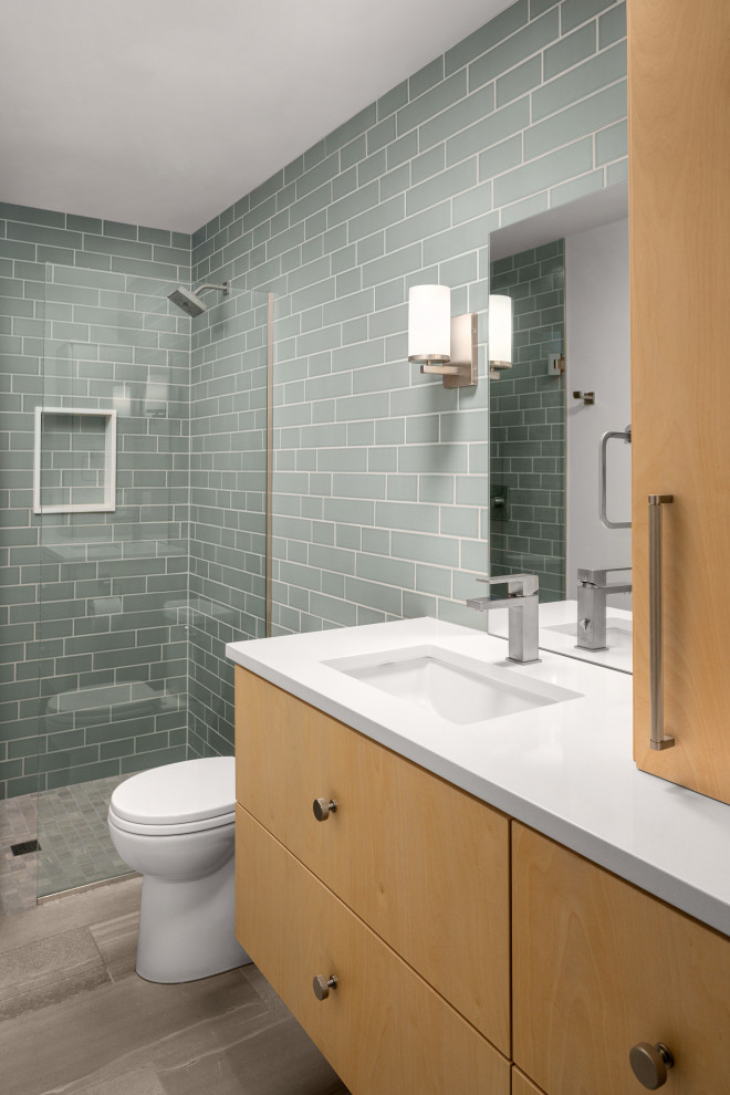 Photo of a medium sized midcentury bathroom in Portland with flat-panel cabinets, light wood cabinets, a built-in shower, green tiles, porcelain tiles, porcelain flooring, a submerged sink, engineered stone worktops, grey floors, a hinged door, white worktops, a wall niche, a single sink and a floating vanity unit.