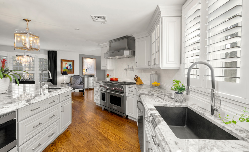 フィラデルフィアにある高級な中くらいなトランジショナルスタイルのおしゃれなキッチン (アンダーカウンターシンク、レイズドパネル扉のキャビネット、白いキャビネット、珪岩カウンター、白いキッチンパネル、石タイルのキッチンパネル、パネルと同色の調理設備、無垢フローリング、茶色い床、白いキッチンカウンター) の写真