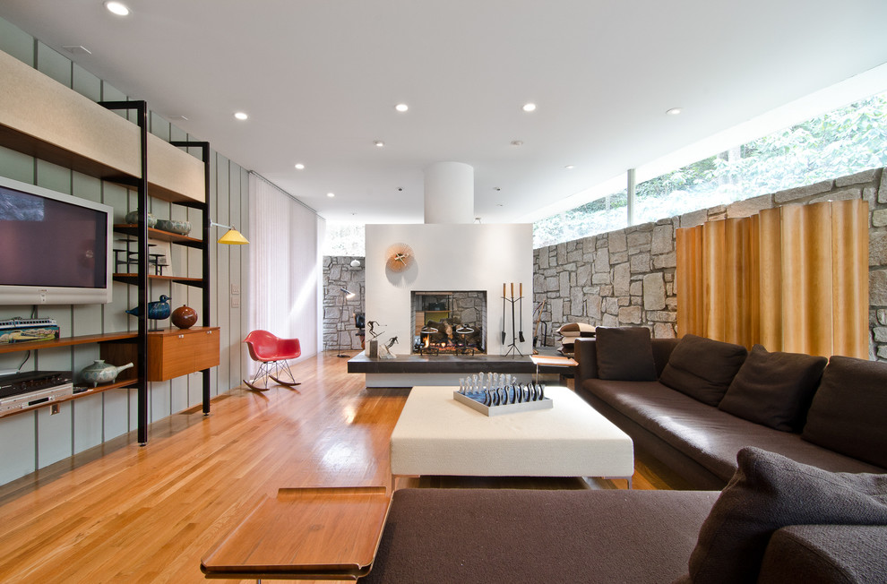 This is an example of an expansive midcentury living room in Atlanta with a two-sided fireplace and a wall-mounted tv.