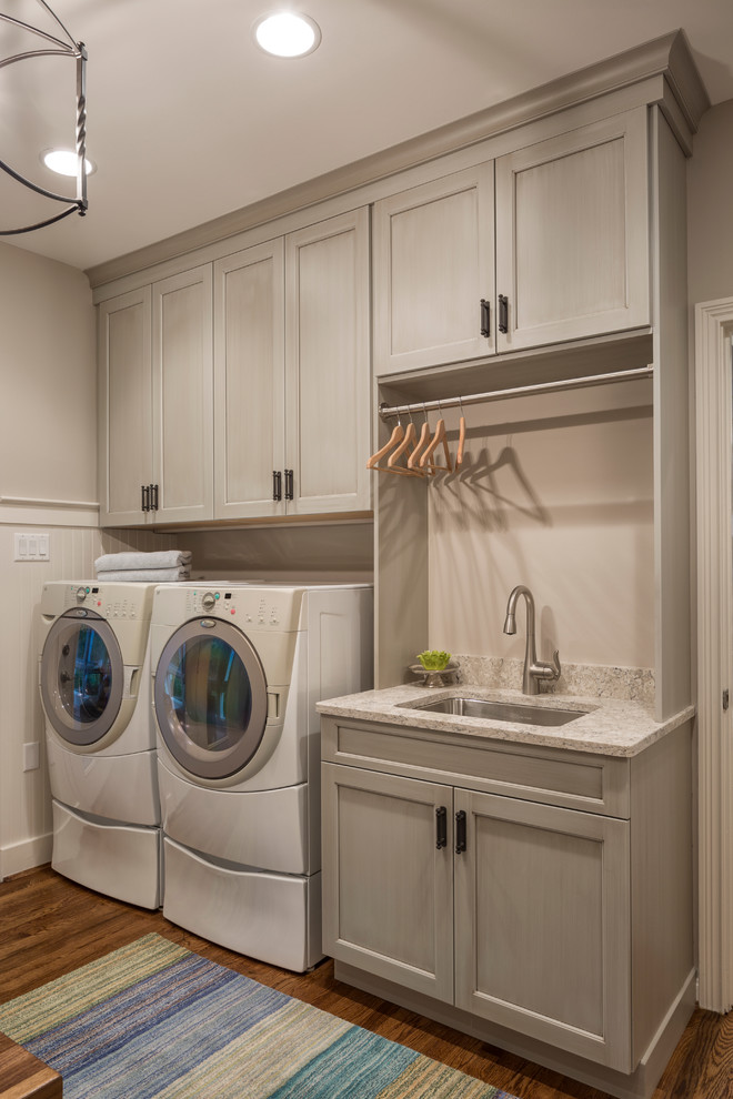 Inspiration for a large transitional dark wood floor utility room remodel in Cincinnati with a drop-in sink, recessed-panel cabinets, white cabinets, wood countertops, gray walls and a side-by-side washer/dryer
