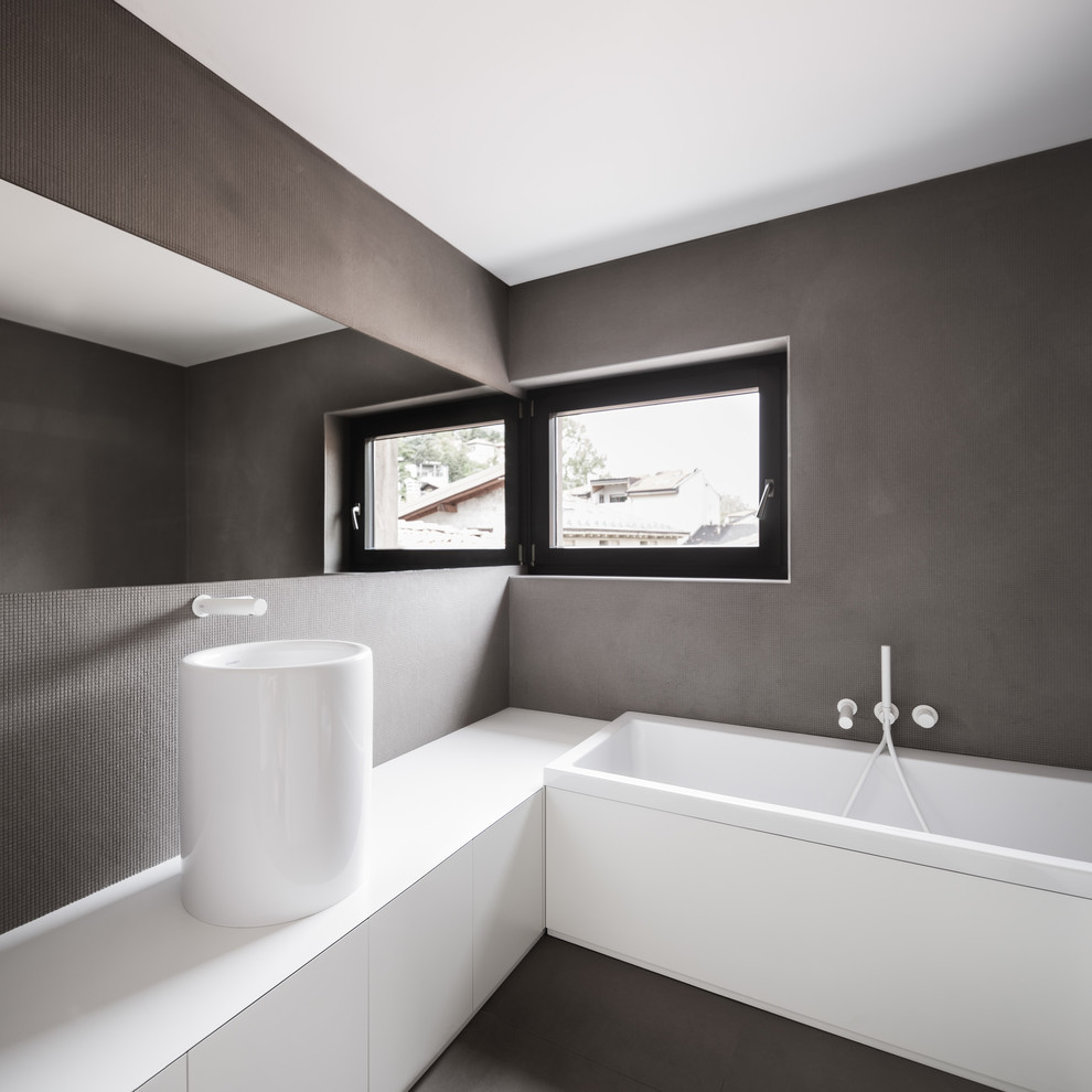 Photo of a modern bathroom in Other with flat-panel cabinets, white cabinets, a drop-in tub, grey walls, porcelain floors, laminate benchtops and a vessel sink.
