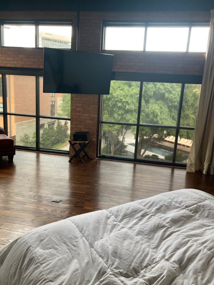 Bedroom - large industrial master medium tone wood floor, brown floor, exposed beam and brick wall bedroom idea in Dallas with orange walls and no fireplace