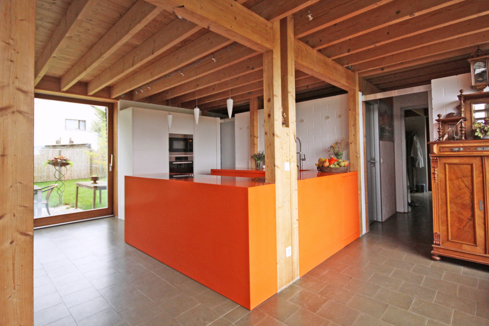 Design ideas for a mid-sized contemporary u-shaped open plan kitchen in Munich with an undermount sink, flat-panel cabinets, orange cabinets, solid surface benchtops, black appliances, grey floor and orange benchtop.