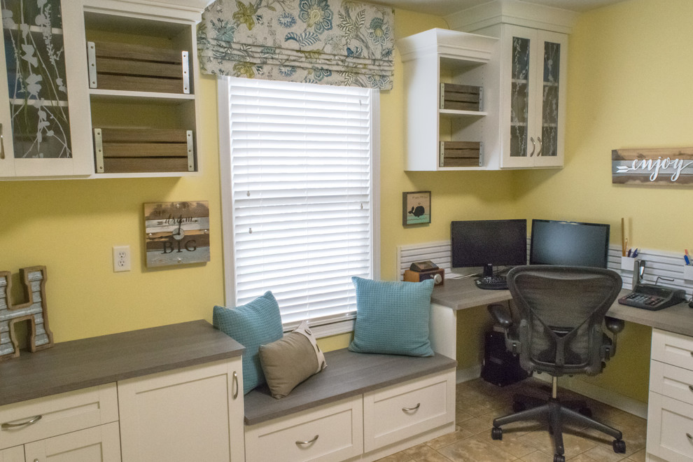 This is an example of a mid-sized transitional home office in Indianapolis with yellow walls, linoleum floors, a built-in desk and brown floor.