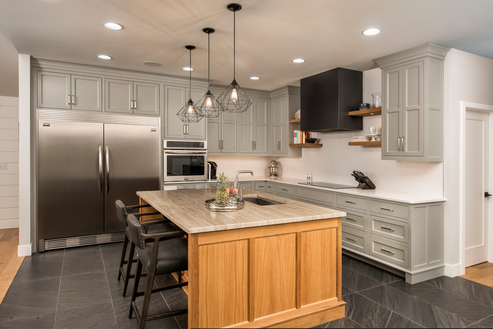 Example of a country l-shaped gray floor kitchen design with shaker cabinets, gray cabinets, white backsplash, stainless steel appliances and an island