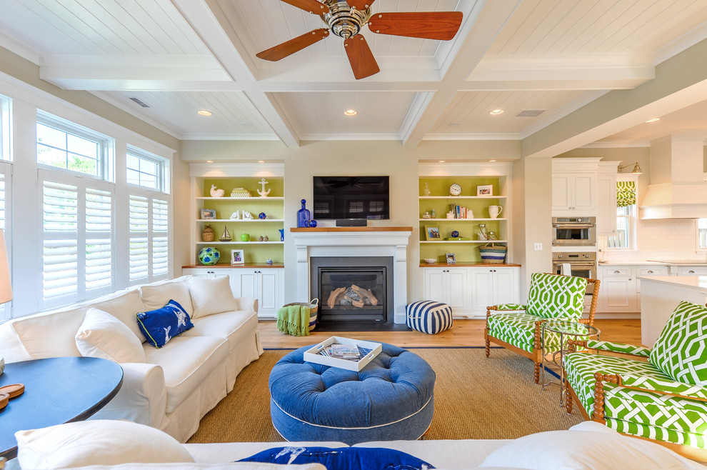 Beach style formal and open concept medium tone wood floor living room photo with beige walls, a standard fireplace and a wall-mounted tv